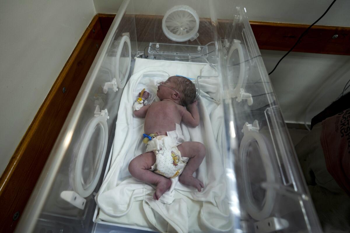 A premature infant lies hooked to oxygen in an incubator.