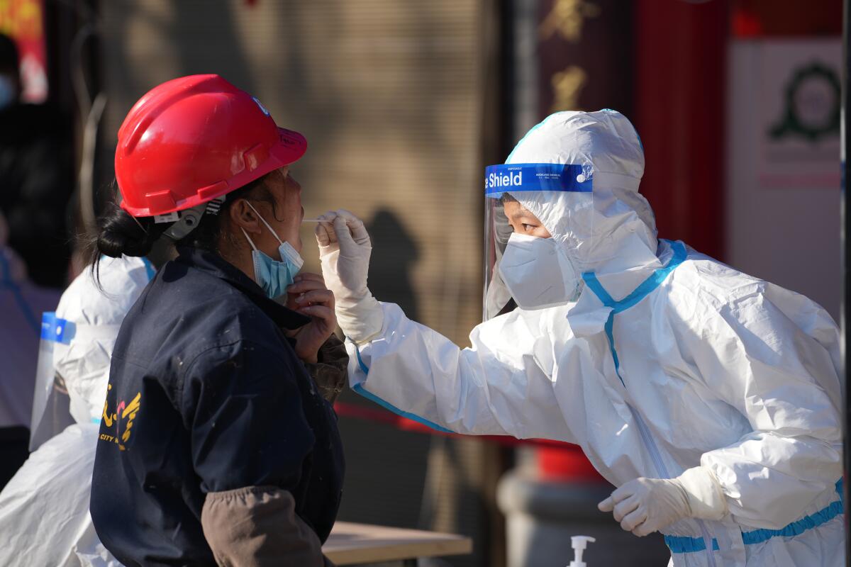 Un trabajador toma una muestra en un sitio de pruebas de coronavirus, en Xi'an, en China.