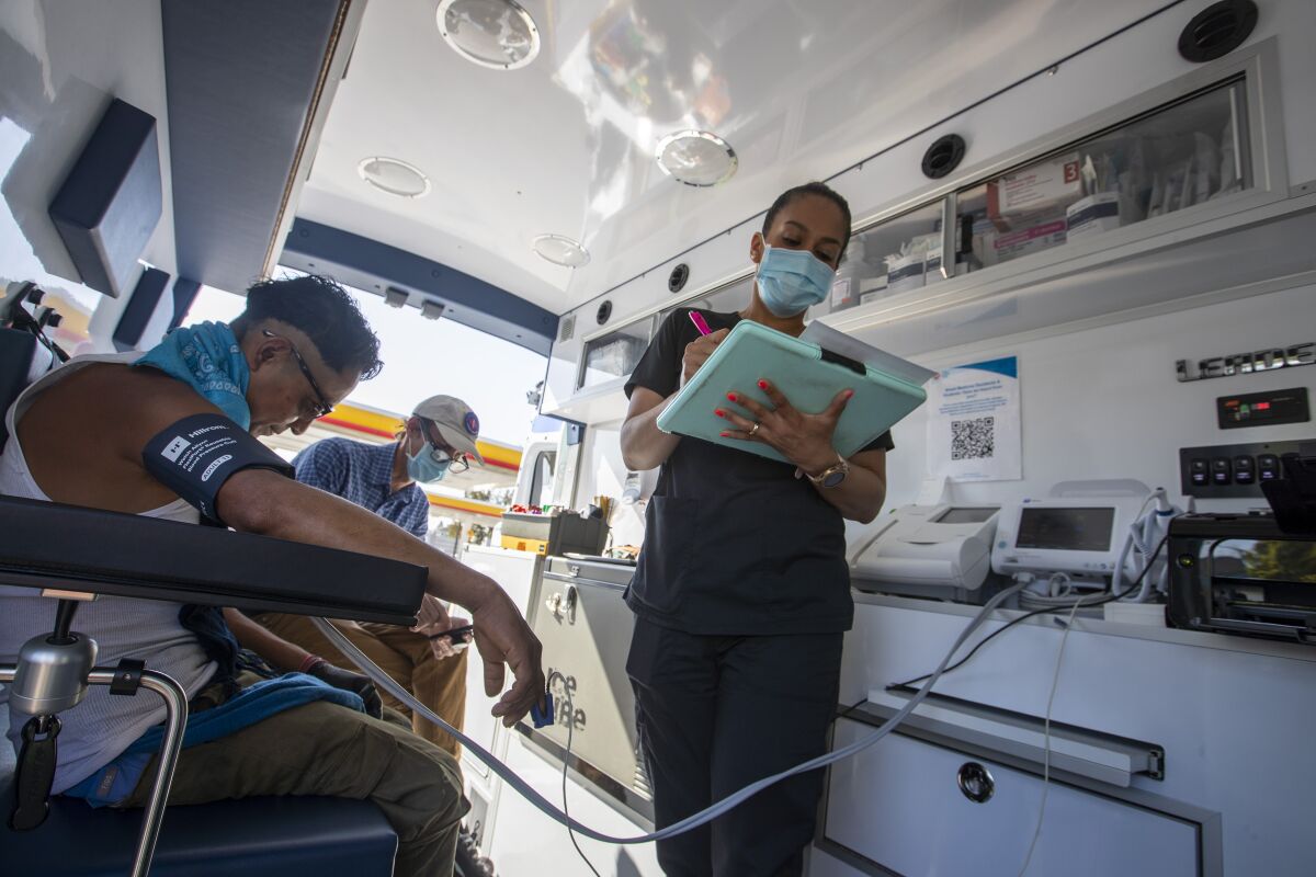 Nurse Jacqueline Ramirez takes blood pressure notes with Rene, a patient, left, and Dr. Coley King.