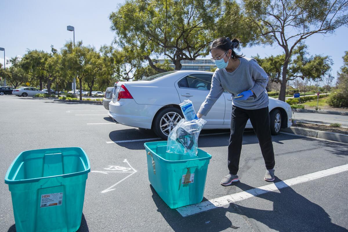 Siman Peng donates supplies Monday at a community drive in Irvine organized by UC Irvine medical students to collect personal protective items including masks, sanitizer and gloves for UCI medical staff.