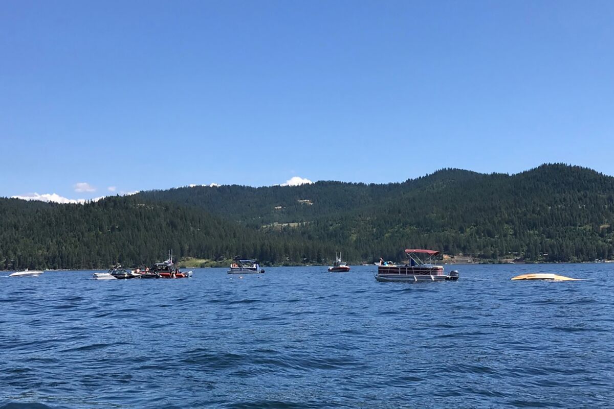 Boaters flag down authorities to a crashed seaplane near Powderhorn Bay on Lake Coeur d'Alene on Sunday, July 5, 2020, south of Coeur d'Alene, Idaho. The downed plane can be seen in the right side of the image. Two people died in a plane crash Sunday over Lake Coeur d’Alene Sunday, the Kootenai County Sheriff’s Office told the Spokane Spokesman-Review. Investigators are checking initial reports that there were a total of eight passengers and crew on the two planes, the sheriff's office said in a statement Sunday night. (Stephanie Hammett/The Spokesman-Review via AP)