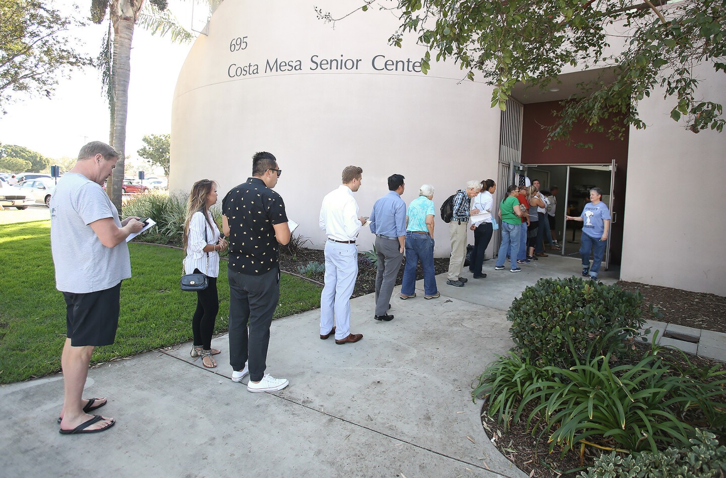 Polling place inspector Laura Bejerano, right, fields questions as voters line up at the Costa Mesa Senior Center on 19th Street on Tuesday, Election Day.