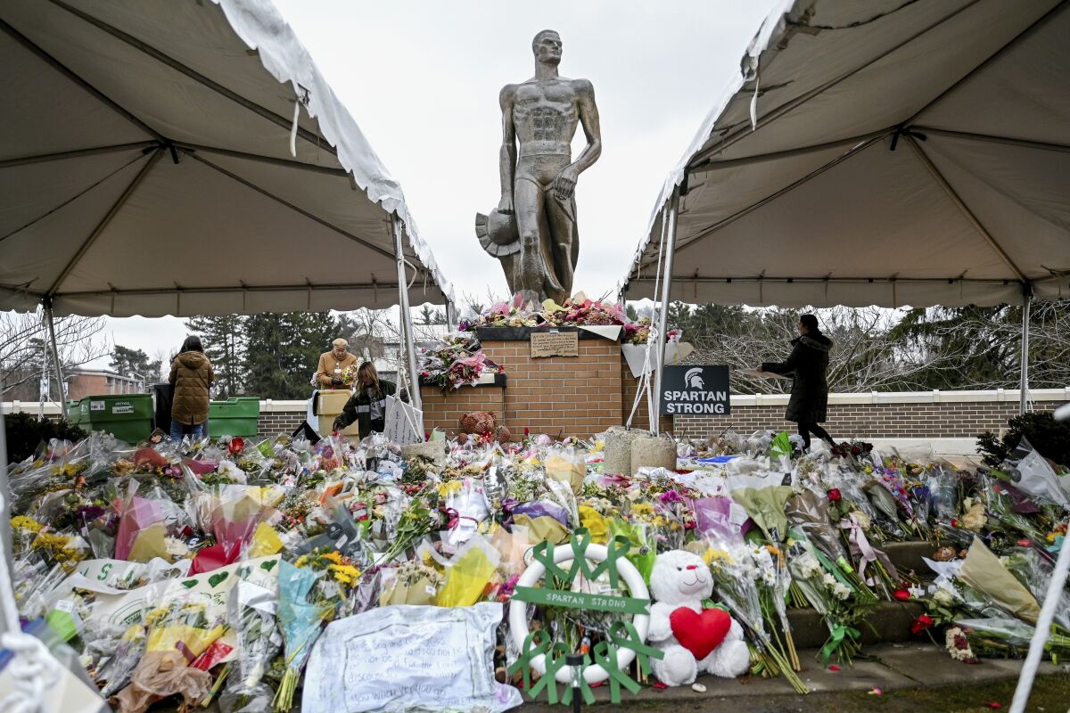 FILE - Volunteers work to clean up the memorial site at the Sparty statue on March 2, 2023, on campus at Michigan State University in East Lansing, Mich. The school said Wednesday, March 29, that the academic building where a gunman fatally shot two students and wounded five others will not hold classes or events through next fall. (Nick King/Lansing State Journal via AP, File)