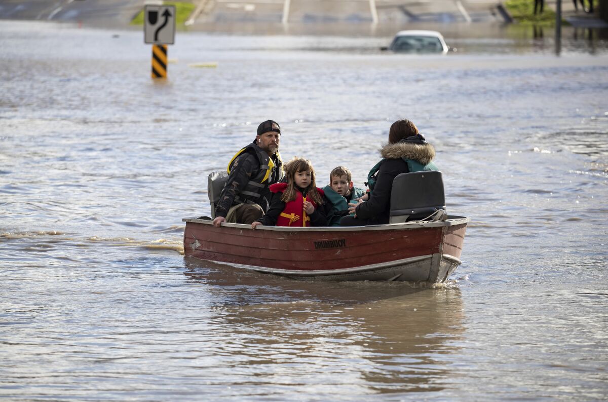 Children ride in a boat on a flooded street