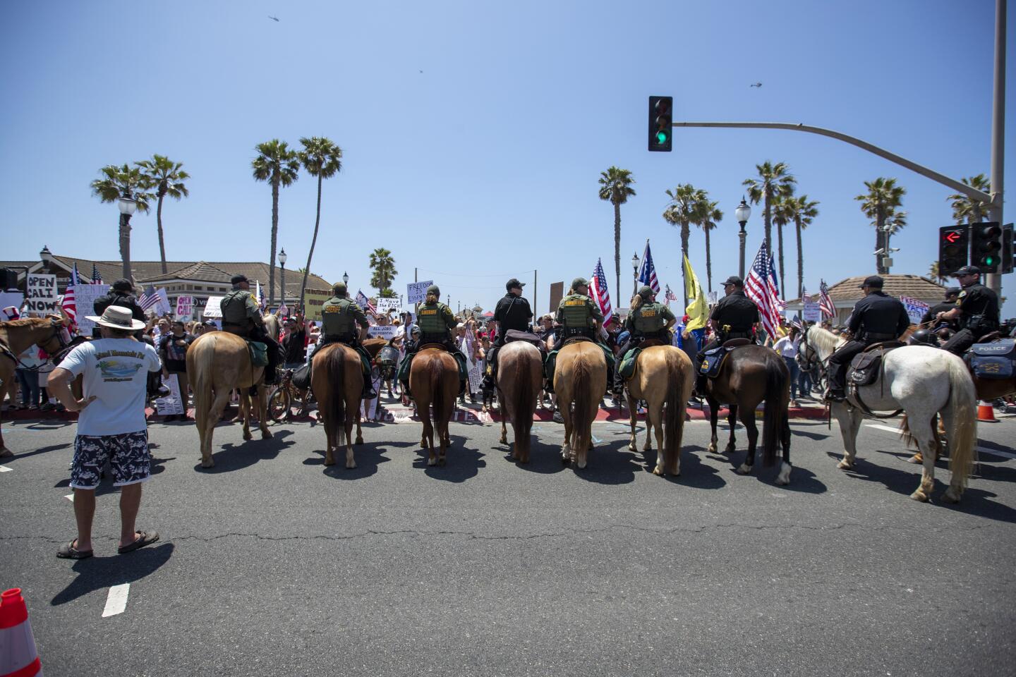 Members of the Orange County Sheriff's Department attempt to keep protesters on the sidewalk at the corners of Main Street and Pacific Coast Highway in Huntington Beach on Friday.