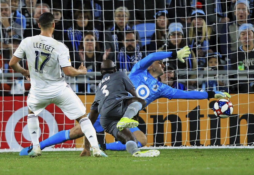 Galaxy midfielder Sebastian Lletget scores past Minnesota United defender Ike Opara and goalie Vito Mannone.
