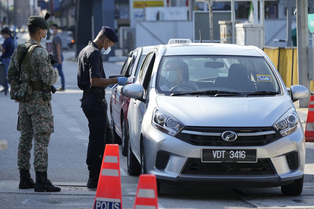 Police check passengers in vehicles at a roadblock during the first day of Full Movement Control Order (MCO) in Kuala Lumpur, Malaysia, Tuesday, June 1, 2021. Malls and most businesses in Malaysia shuttered Tuesday as the country began its second near total coronavirus lockdown to tackle a worsening pandemic that has put its healthcare system on the verge of collapse. (AP Photo/Vincent Thian)