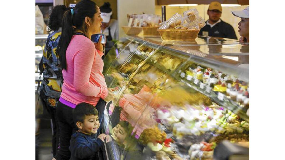 A little boy admires the colorful pastries as his mother places an order at Porto's Bakery & Cafe in Glendale. The bakery has thrived for four decades, fending off national chains, recessions and low-carb fads along the way.