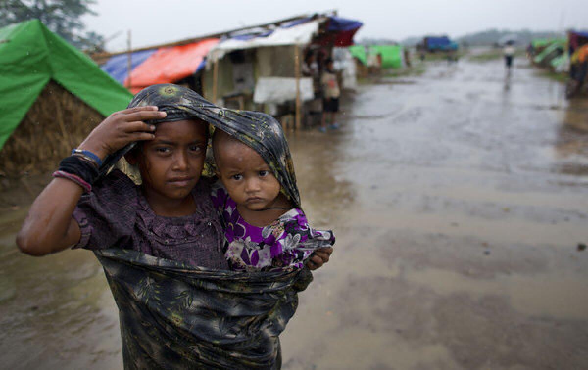 A Rohingya Muslim girl walks with a sibling in the rain at a makeshift camp for Rohingya people in Sittwe in northwestern Rakhine state, ahead of the arrival of Cyclone Mahasen. A boat capsized off the Myanmar coast as Rohingya fled, and 60 people are believed missing.