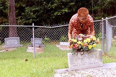 Maevella Moore fixes flowers on the grave of her husband, Oneal Moore, in the all-black cemetery in Varnado, Louisiana.