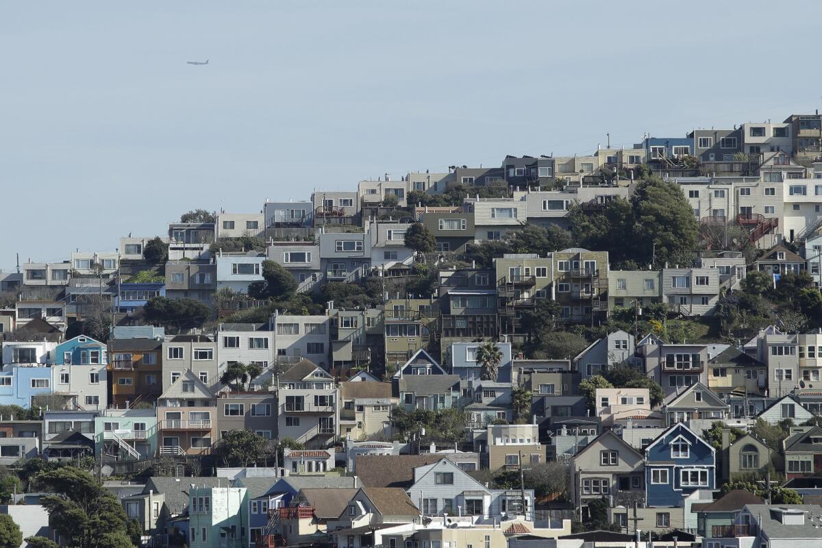 A plane flies over homes and residential buildings in San Francisco.