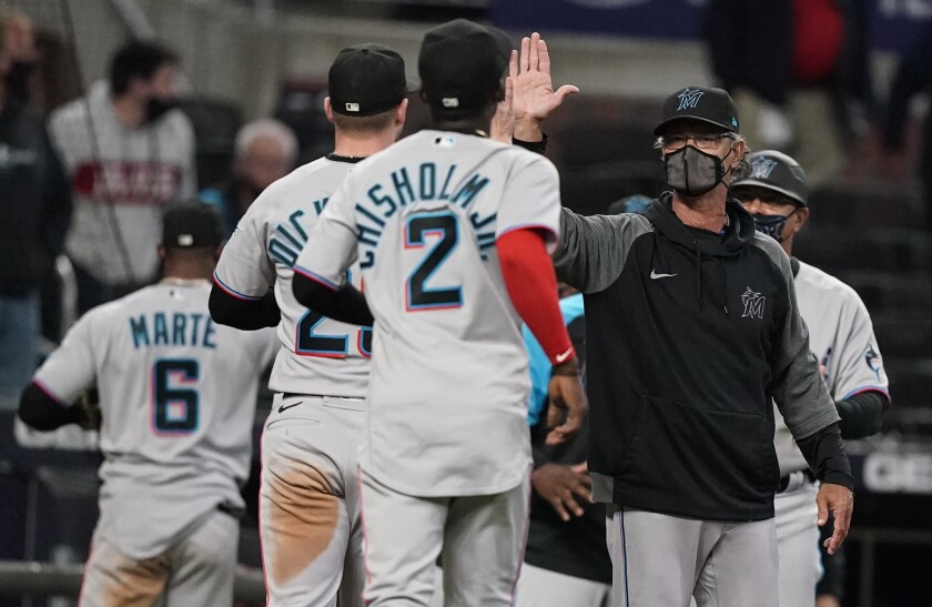 Miami Marlins manager Don Mattingly high-fives players after the team's 6-5 win over the Atlanta Braves in 10 innings in a baseball game Wednesday, April 14, 2021, in Atlanta. (AP Photo/Brynn Anderson)