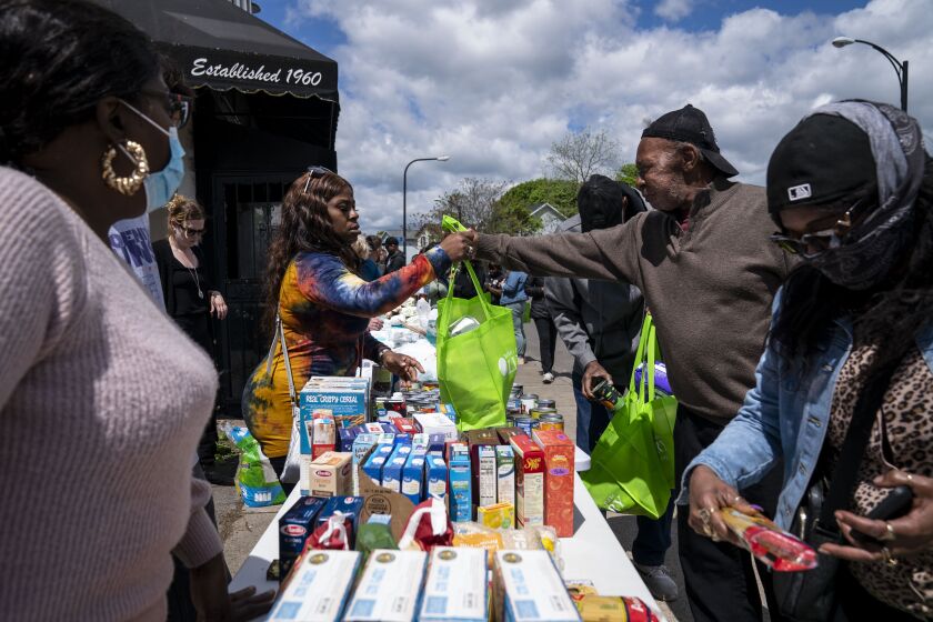 BUFFALO, NY - MAY 17: Eddie Colbert, 71, second from right, and others pick up food and supplies from a food distribution event put on by Buffalo Community Fridge along Ferry street, just blocks away from Tops Friendly Market at Jefferson Avenue and Riley Street on Tuesday, May 17, 2022 in Buffalo, NY. The Supermarket was the site of a fatal shooting of 10 people at a grocery store in a historically Black neighborhood of Buffalo by a young white gunman is being investigated as a hate crime and an act of "racially motivated violent extremism," according to federal officials. (Kent Nishimura / Los Angeles Times)