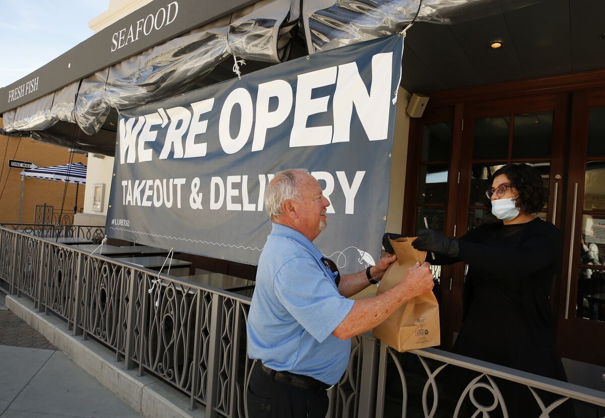 Customer picks up an order at Lure Fish House in downtown Ventura