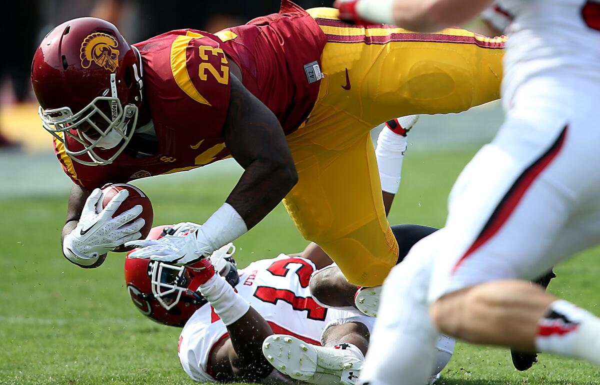 USC tailback Tre Madden bowls over Utah defensive back Eric Rowe during a game last season.