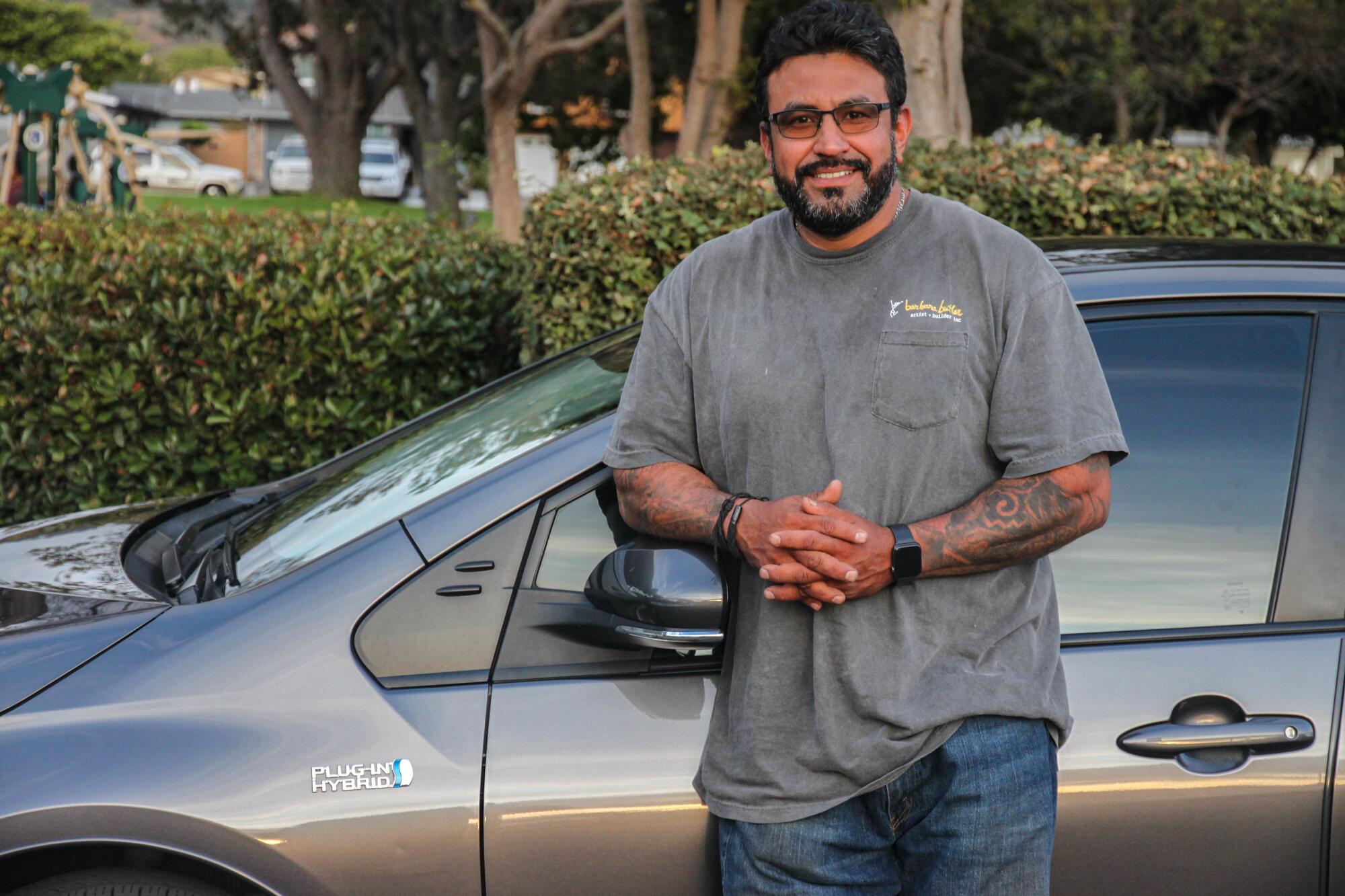 A man stands next to his Toyota Prius Prime. 