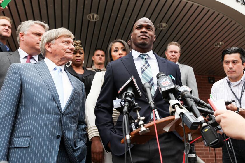 Minnesota Vikings running back Adrian Peterson, center, and his attorney Rusty Hardin, left, speak to the media Nov. 4 after pleading no contest to a misdemeanor assault charge in Conroe, Texas.