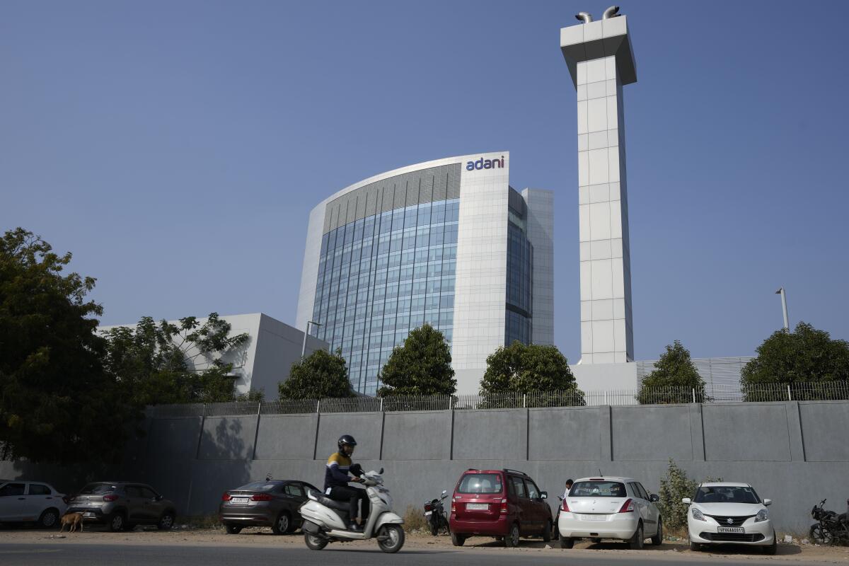 FILE- A motorist rides past Adani Corporate House in Ahmedabad, India, Friday, Jan. 27, 2023. Asia’s richest man, Gautam Adani, saw his companies shed tens of billions of dollars in market value after short-selling firm Hindenburg Research accused him of “pulling the largest con in corporate history,” triggering a massive sell-off of Adani stocks.(AP Photo/Ajit Solanki, File)