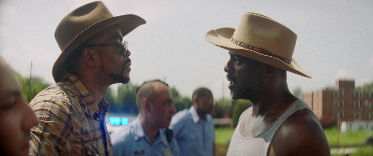 Cliff “Method Man” Smith and Idris Elba, wearing cowboy hats, look at each other