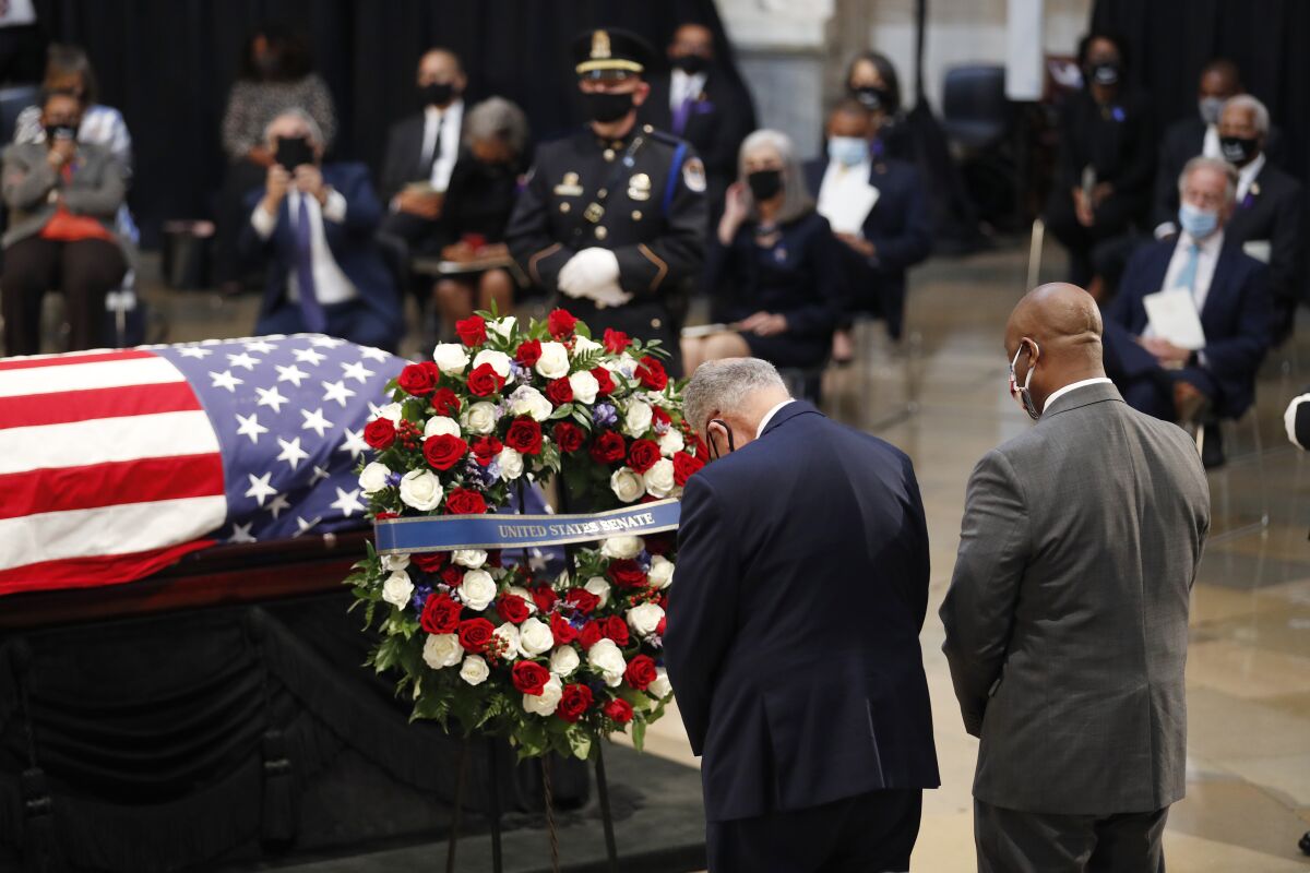 Sens. Charles E. Schumer, left, and Tim Scott attend a memorial service for John Lewis at the Capitol in Washington.