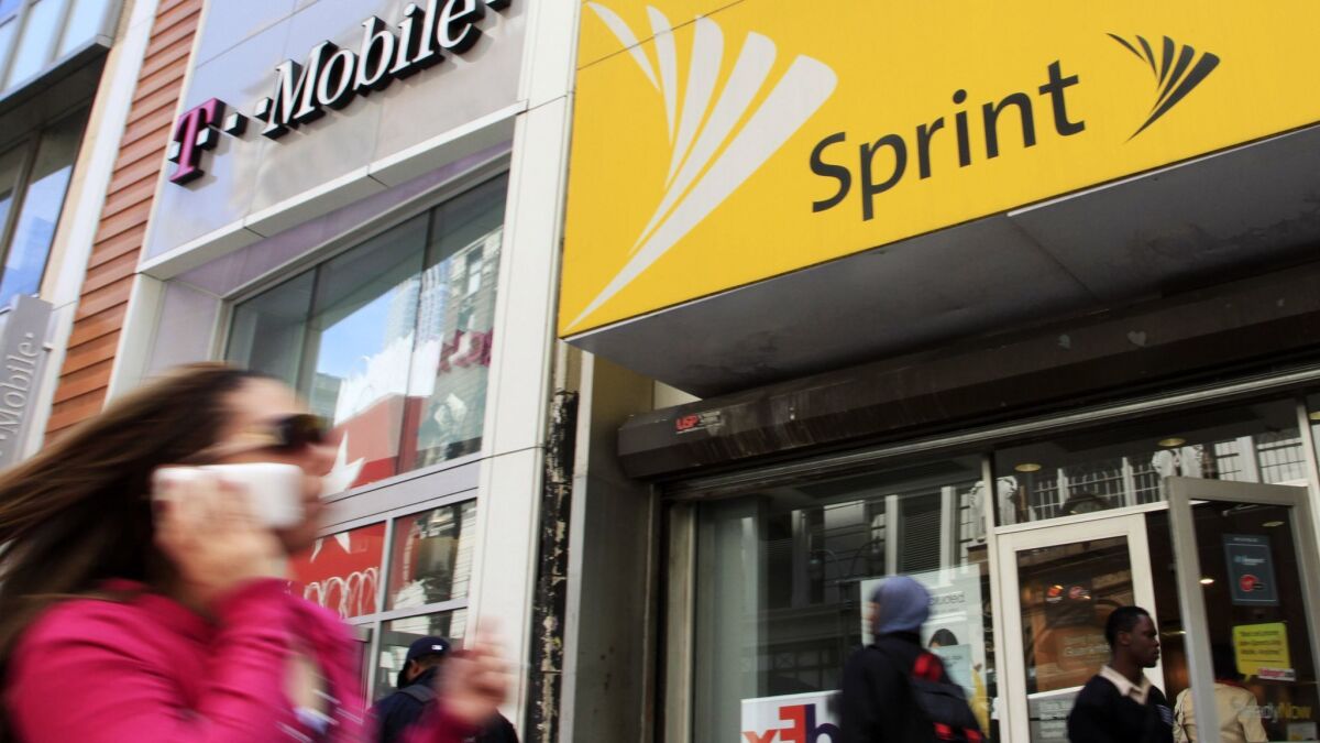 A woman using a cellphone walks past T-Mobile and Sprint stores in New York in 2010.