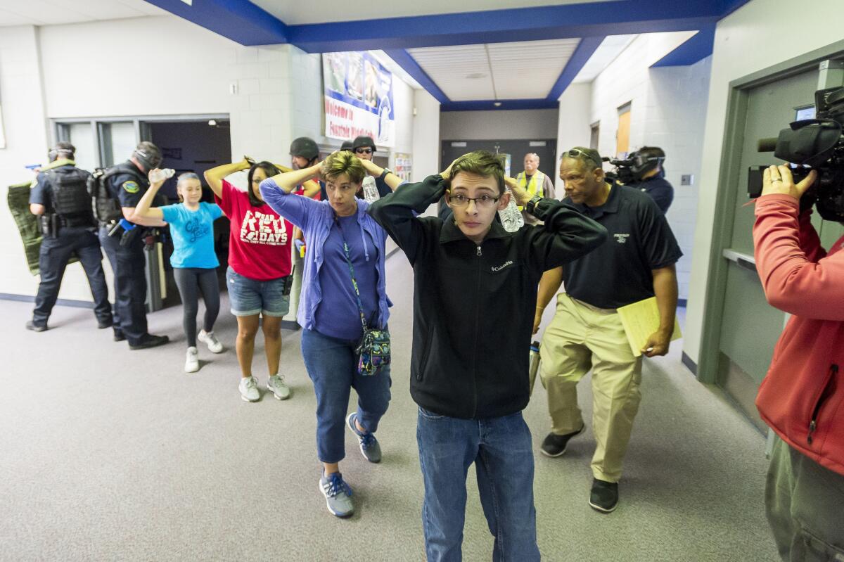 Students walk out of school with their hands on their heads.