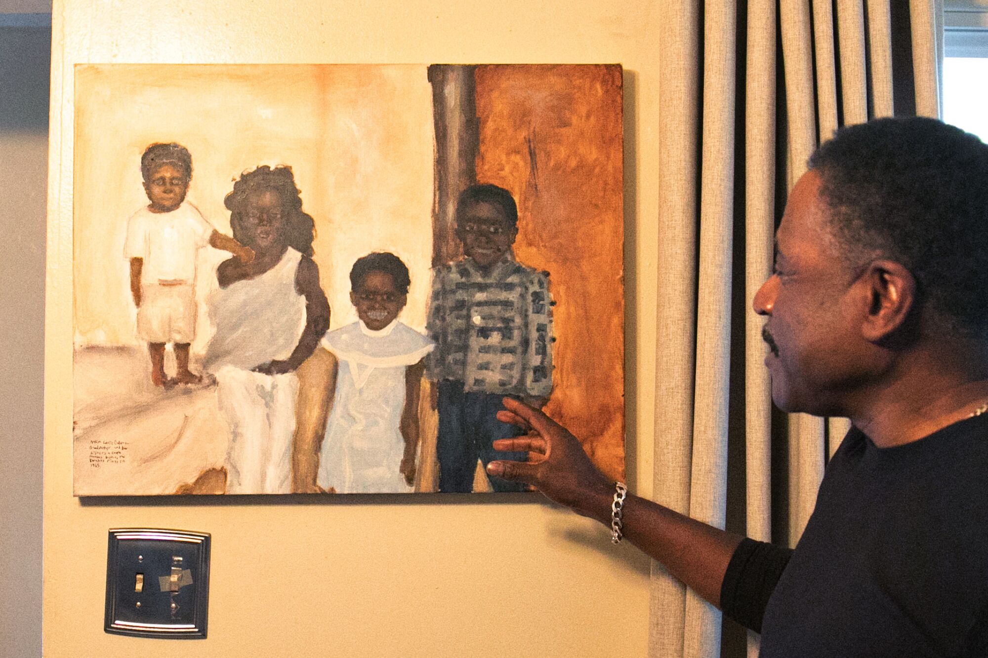 A man stands pointing to a painting of a family