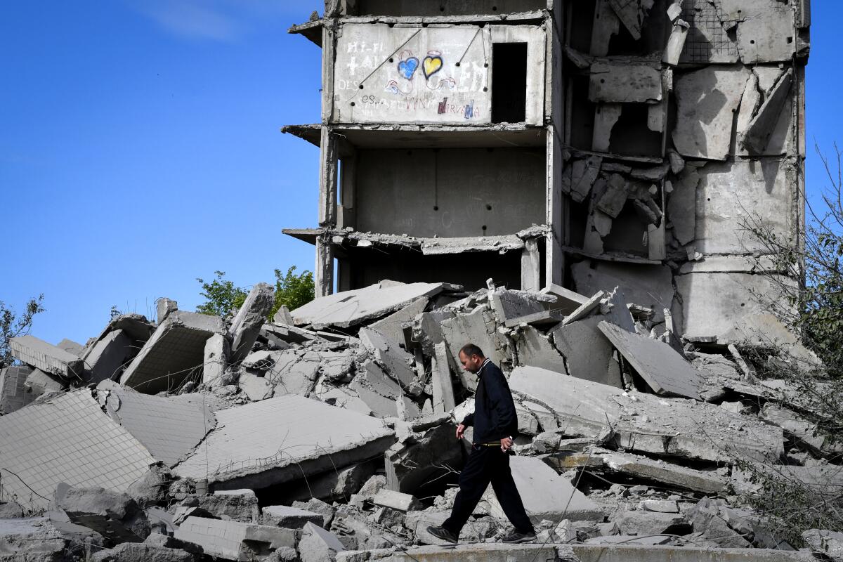 A man  walks past destroyed concrete rubble of a building
