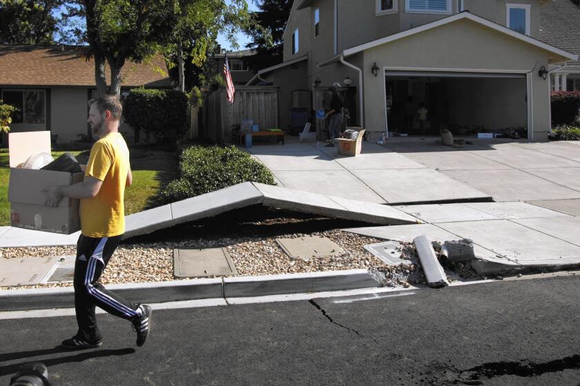 Scott Whitlock walks over a stretch of buckled sidewalk while helping his parents move out of their damaged home. The fault line was unknown to geologists before it ruptured in August.