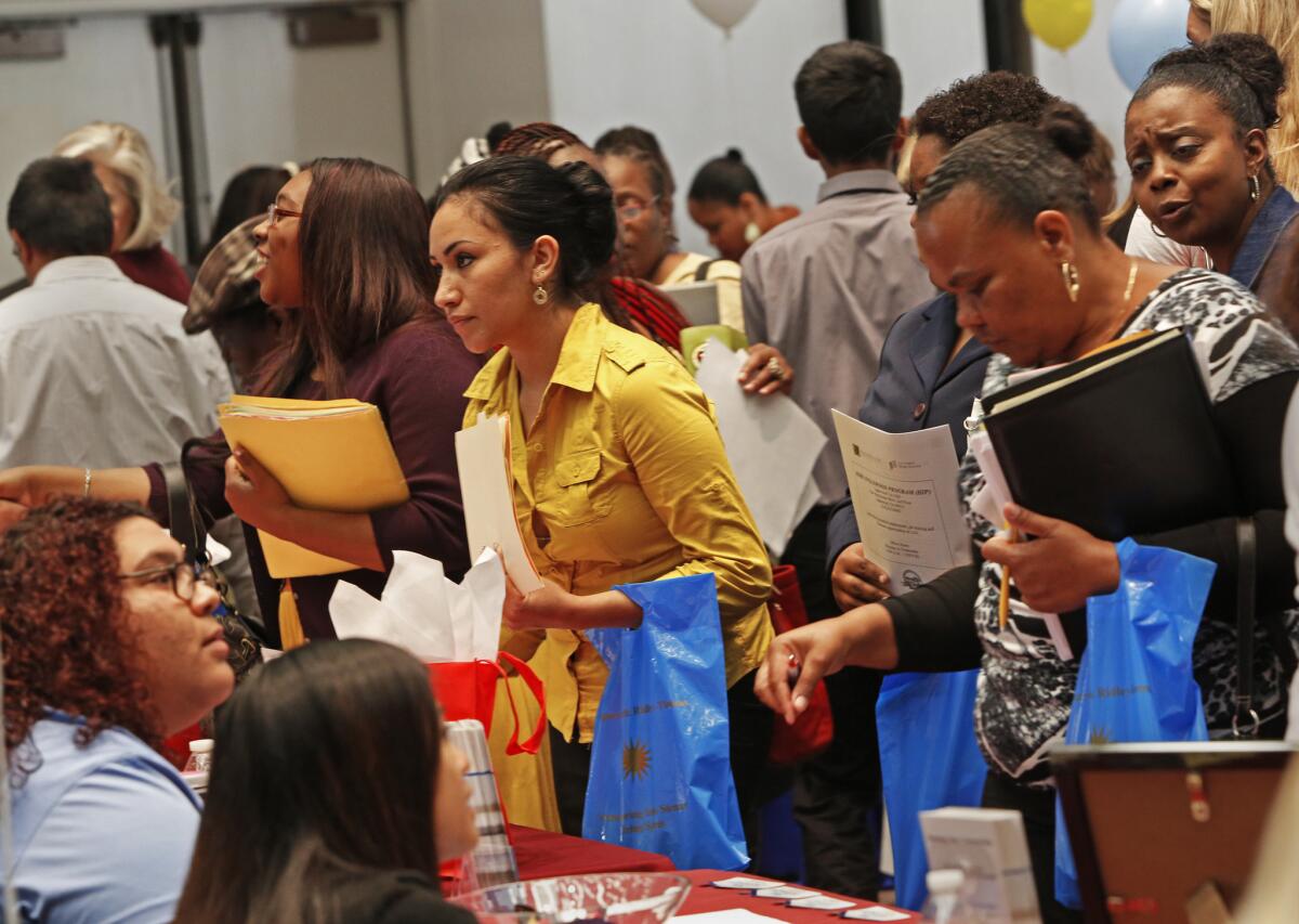 Initial jobless claims fell last week after climbing for three weeks. Above, job seekers gather at a career fair in Carson last week.
