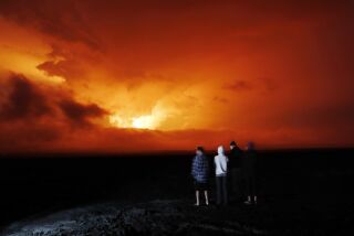 Unas personas observan la erupción del volcán Mauna Loa, el lunes 28 de noviembre de 2022, cerca de Hilo, Hawai. (AP Foto/Marco Garcia)