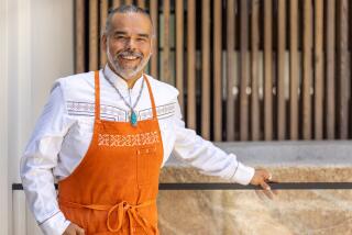 Wes Avila, chef-owner of Mexican steakhouse MXO, stands smiling in orange apron outside the restaurant 