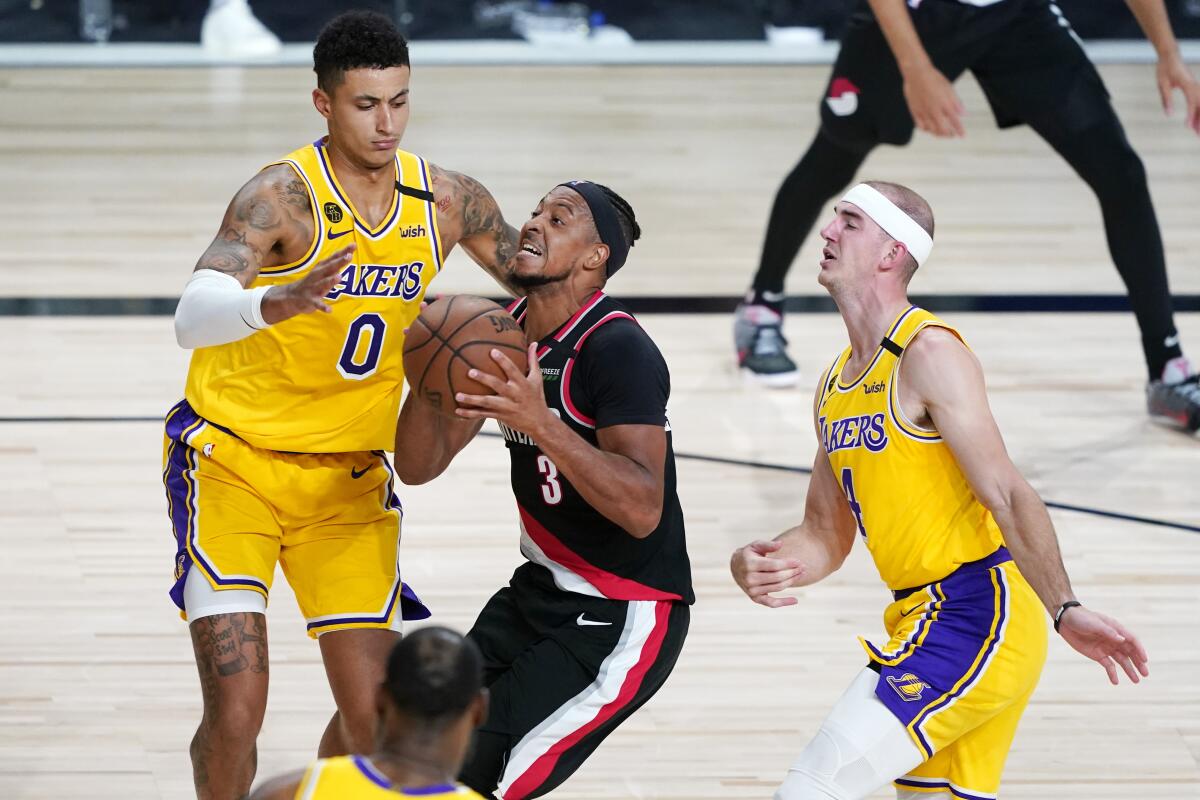 The Trail Blazers' CJ McCollum drives against the Lakers' Kyle Kuzma, left, and Alex Caruso on Aug. 29, 2020.