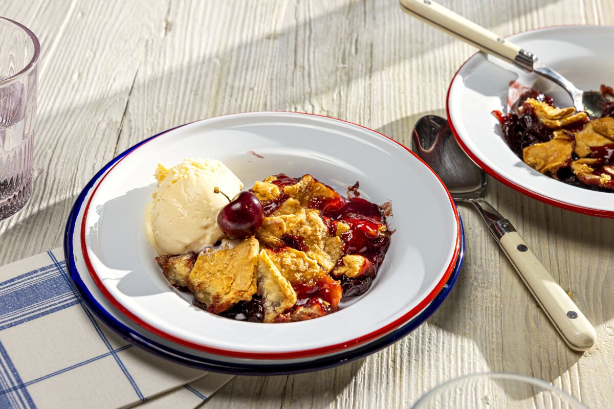 Closeup of a dish with cherry pie and a scoop of vanilla ice cream.