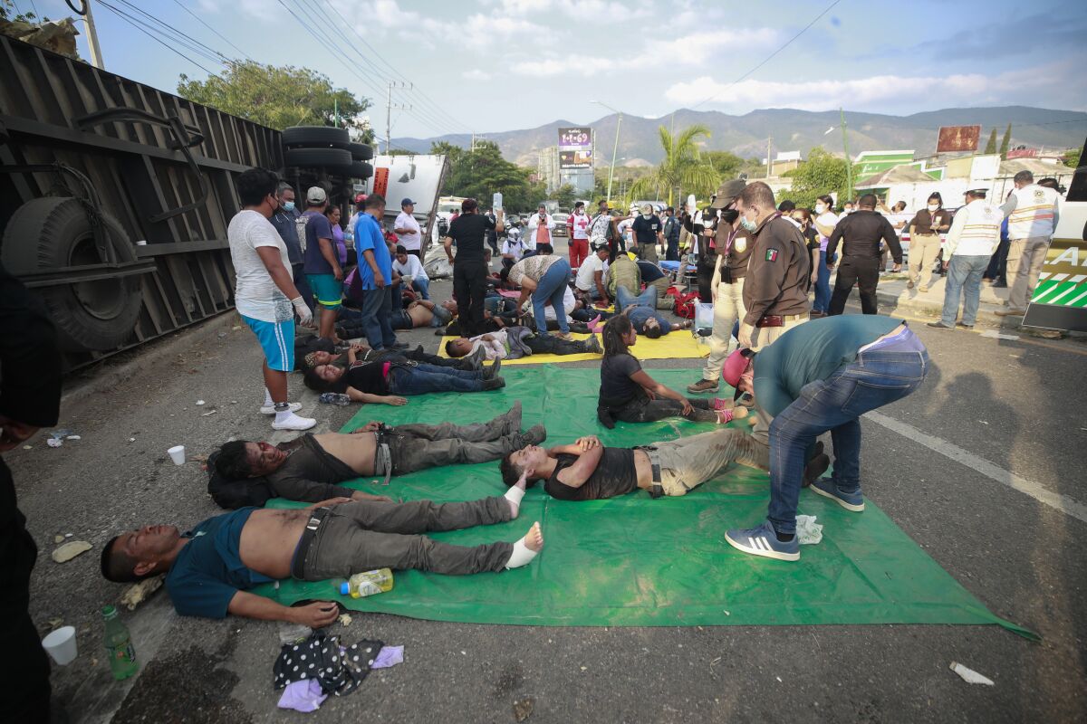 Injured people are cared for next to an overturned truck