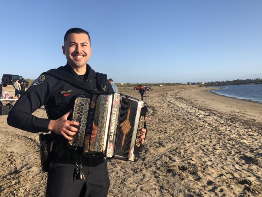 San Diego police Officer Gary Gonzales plays the accordion on Fiesta Island after an interview on Sunday.