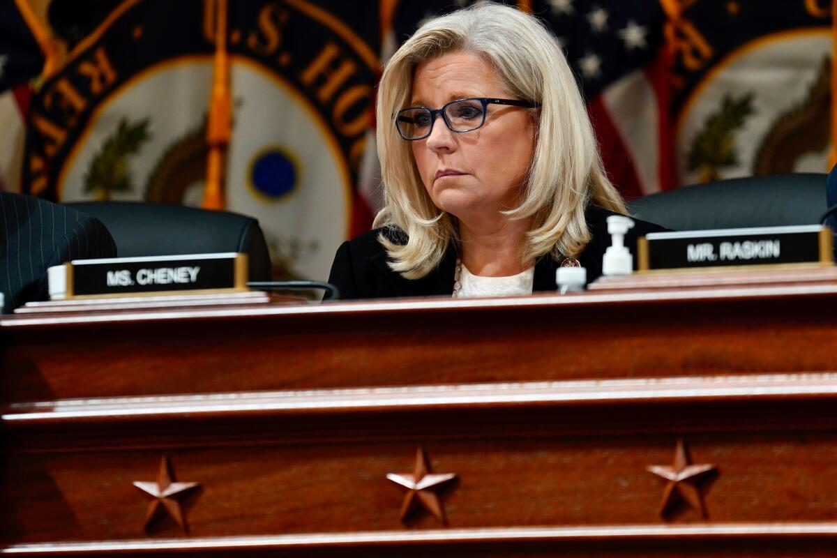 A woman sits at a desk behind the nameplate "Ms. Cheney."