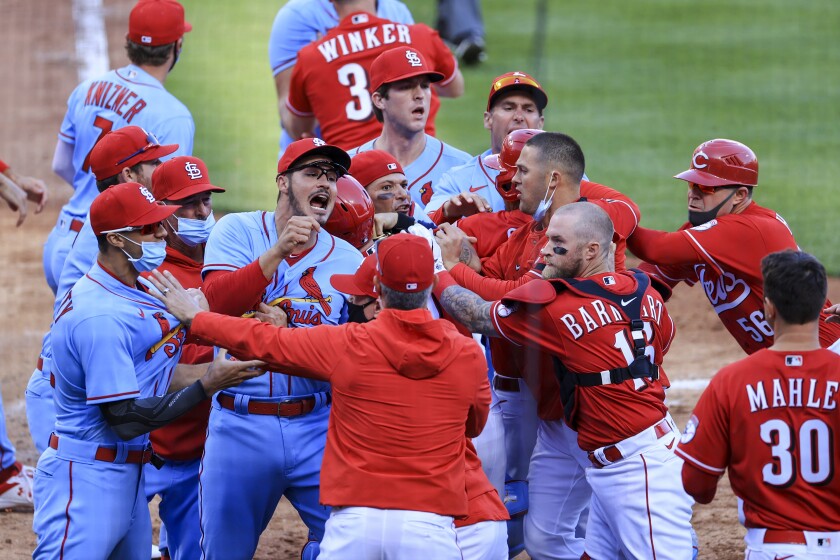 St. Louis Cardinals' Nolan Arenado, center left, reacts alongside teammate catcher Yadier Molina, center, as they scrum with members of the Cincinnati Reds during the fourth inning of a baseball game in Cincinnati, Saturday, April 3, 2021. (AP Photo/Aaron Doster)