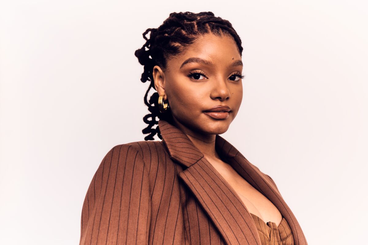 Halle Bailey, in a striped suit, facing the camera