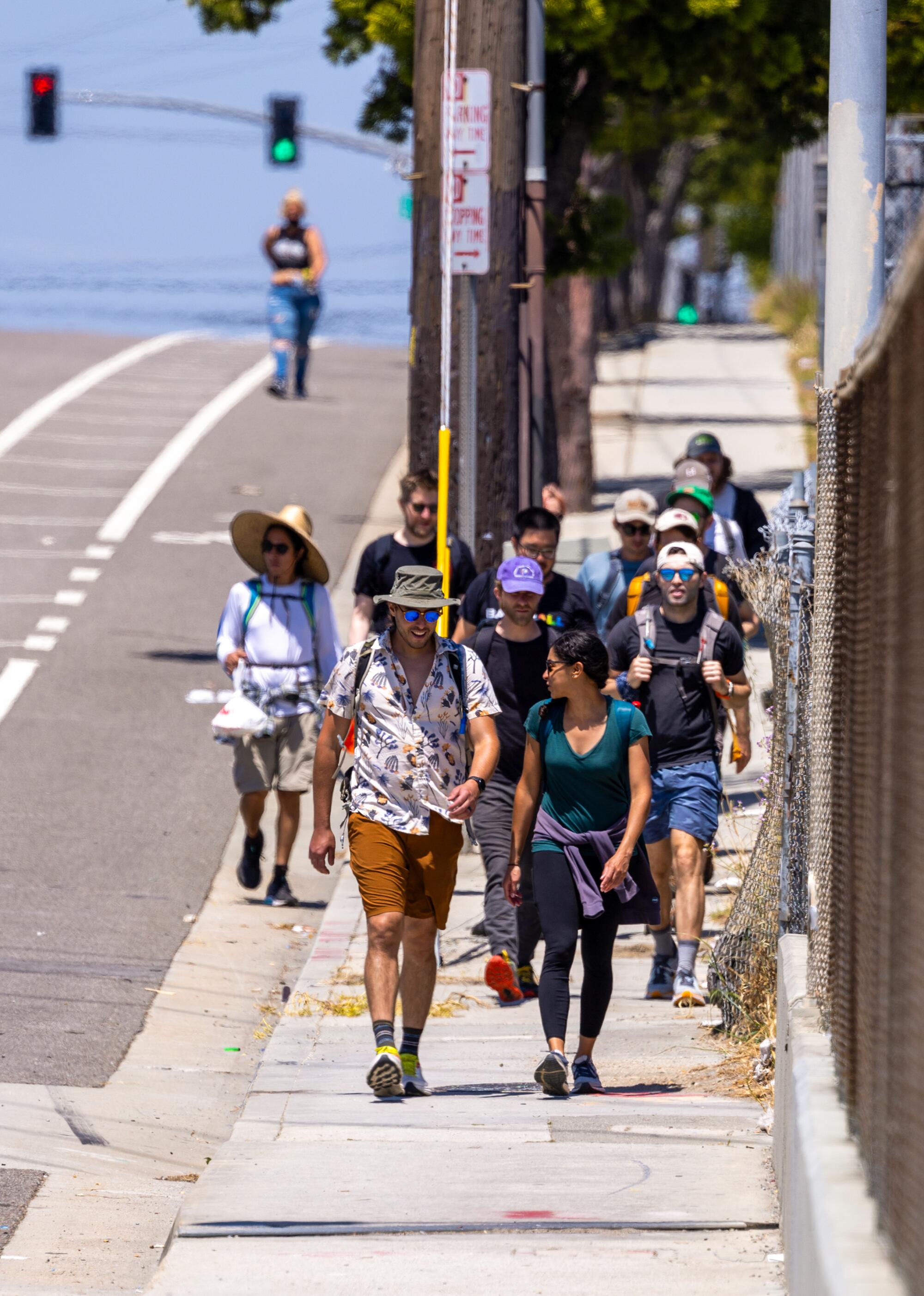 A group of people walk along the sidewalk over the 105 Freeway. 