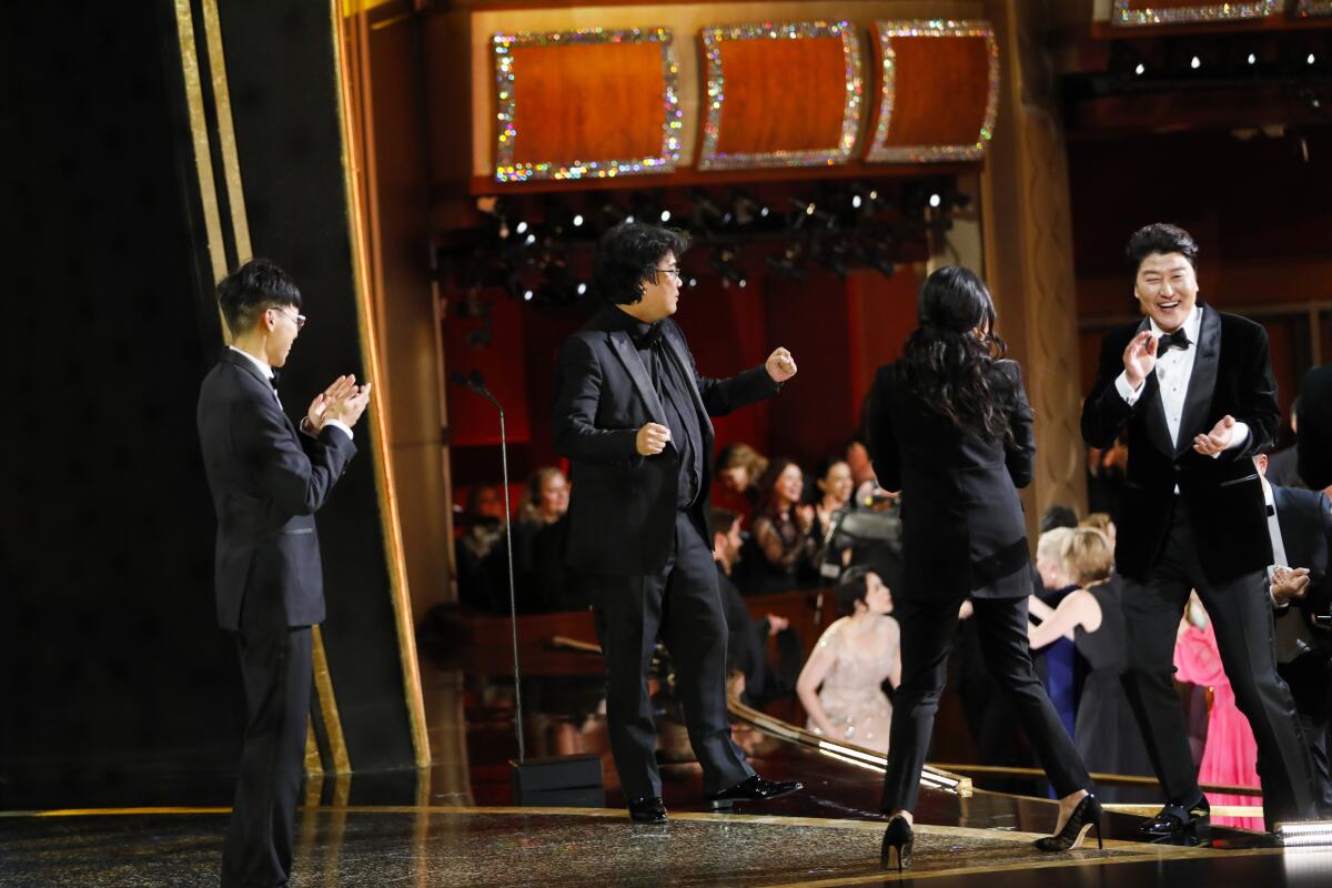 Bong Joon Ho, center, and Song Kang Ho, right reacts to winning best picture for "Parasite" as seen from backstage at the 92nd Academy Awards.