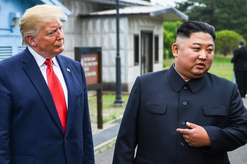 North Korean leader Kim Jong Un, right, points sideways to President Trump