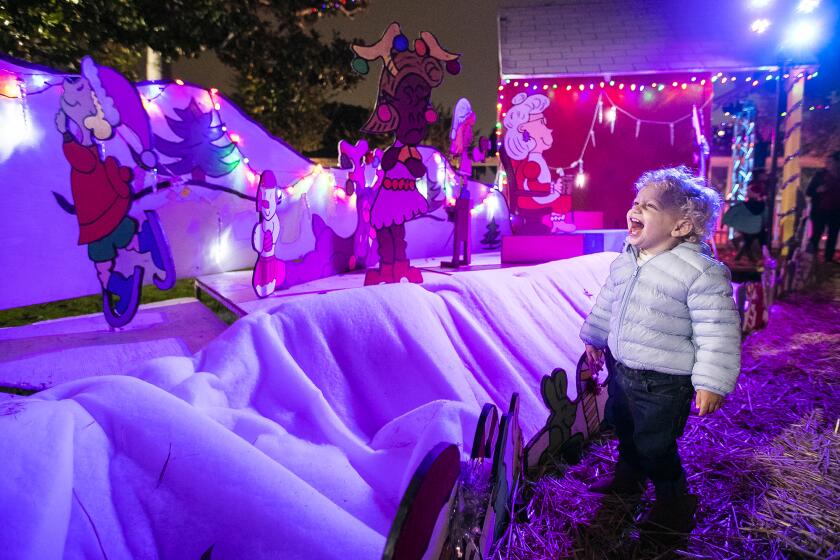 Beckham Di Figlia, 16-months-old, from Costa Mesa laughs while viewing the Snoopy House holiday display at Costa Mesa City Hall on Friday, December 13.