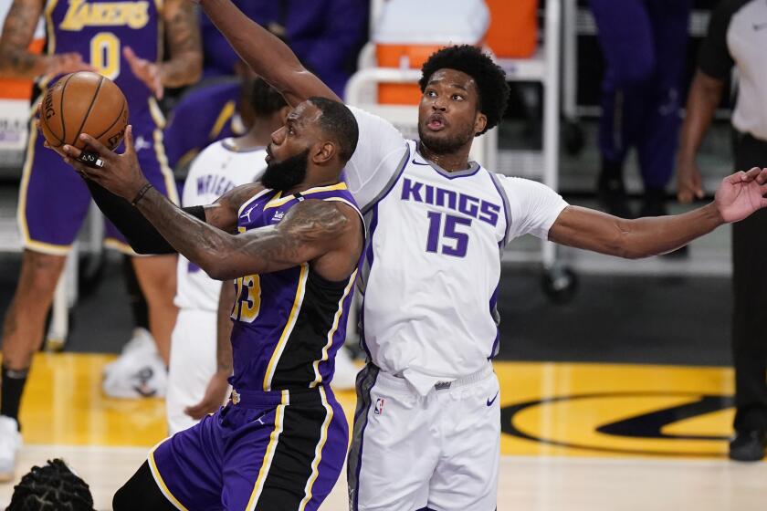 Lakers forward LeBron James scores past Kings center Damian Jones on April 30, 2021, at Staples Center.