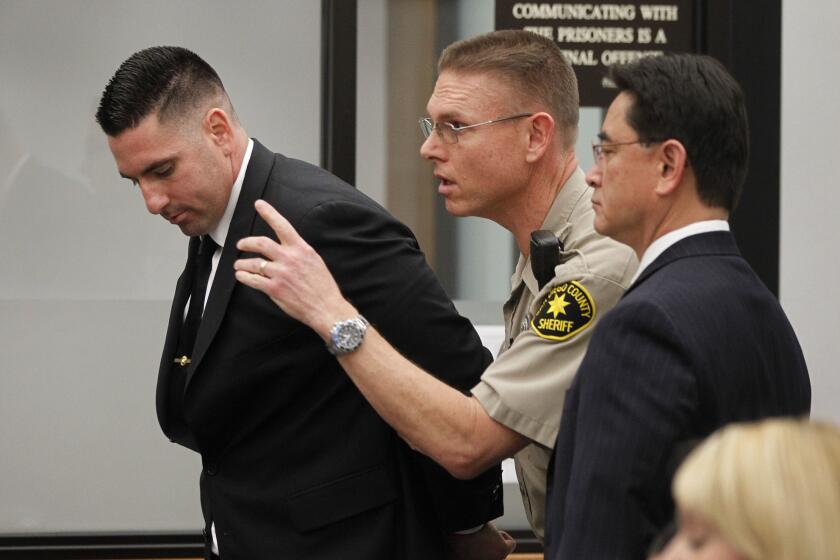 After being handcuffed, former Deputy Richard Fischer, left, is directed out of the courtroom by a court bailiff as he is taken into custody after his arraignment at the Vista courthouse on Thursday.