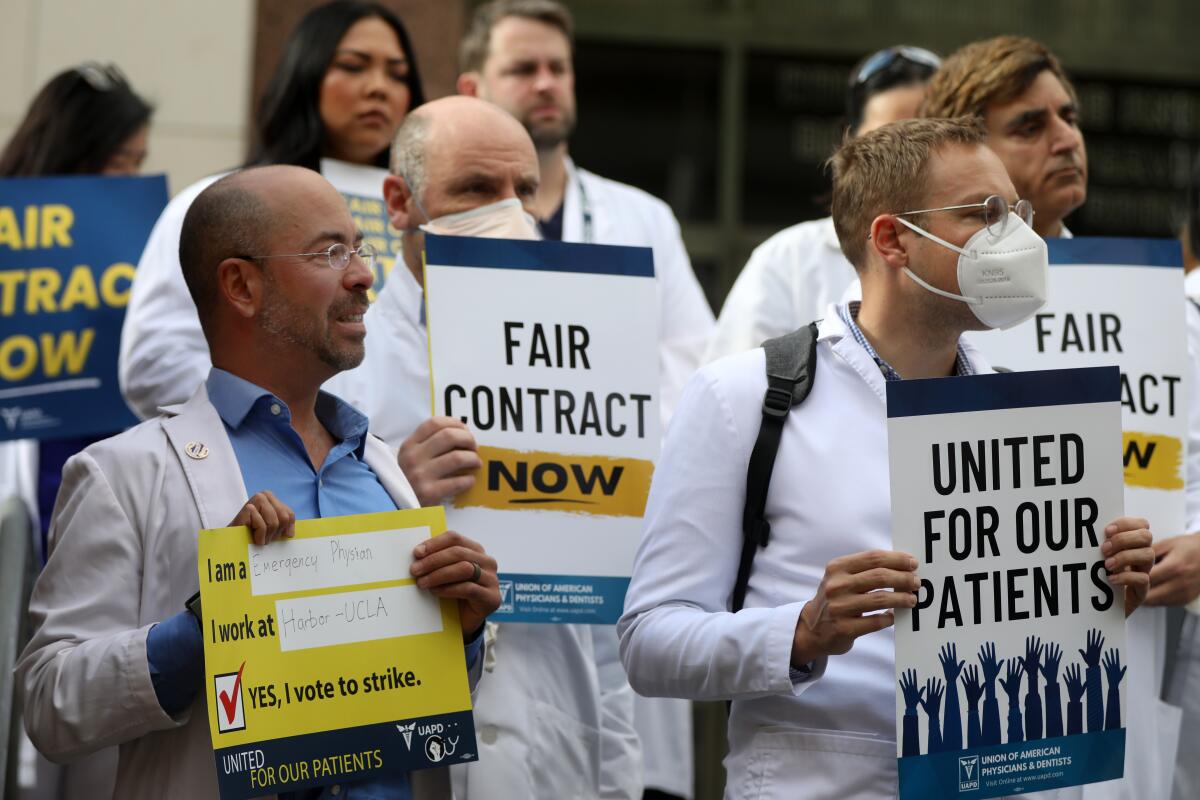 People in white coats hold signs reading "United For Our Patients" and "Fair Contract Now."