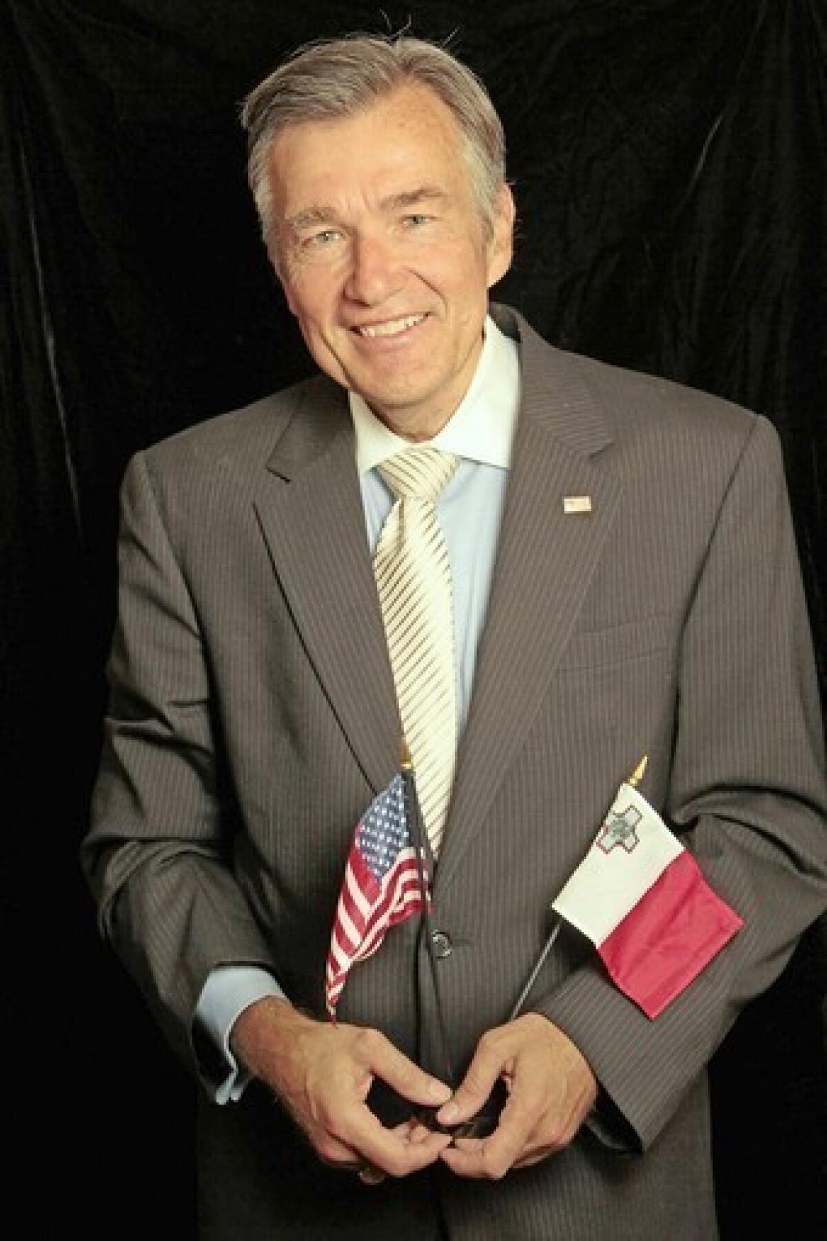 Douglas Kmiec is seen in his office at Pepperdine Law School in Malibu holding both an American flag and the flag of Malta.