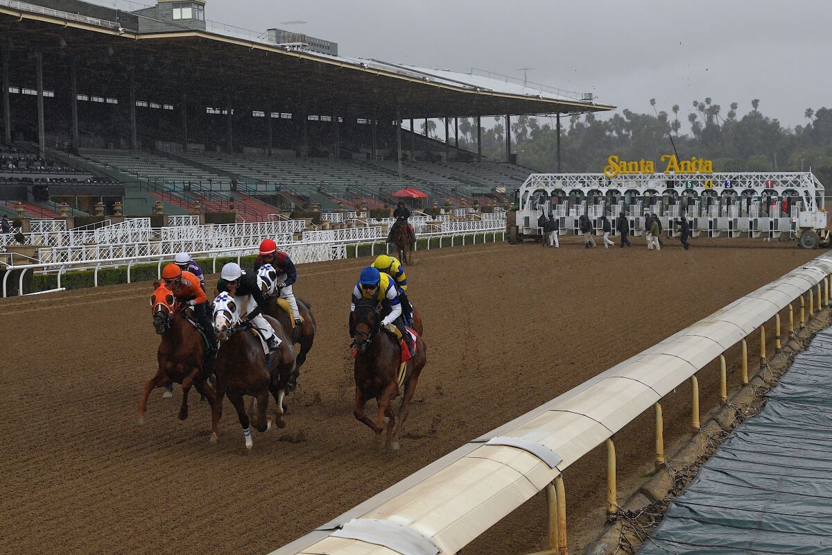 FILE - In this March 14, 2020, file photo, horses run in the fourth race at Santa Anita Park in front of empty stands in Arcadia, Calif. Opening day of Santa Anita’s fall season will be pushed back a week until Sept. 25 because of poor air quality from a wildfire burning near the Southern California racetrack. (AP Photo/Mark J. Terrill, File)