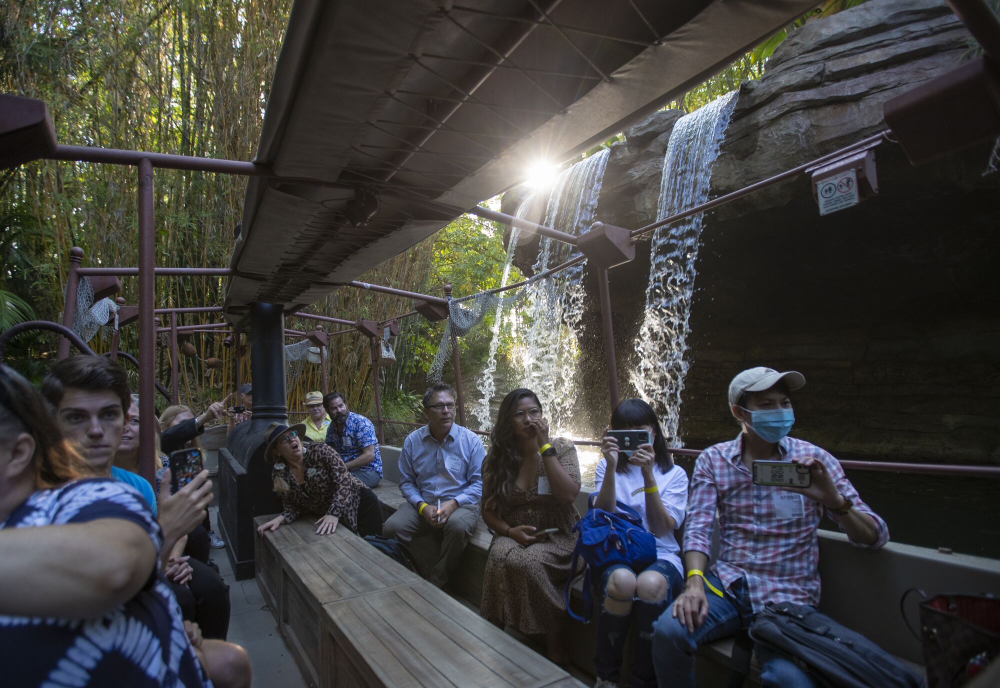 Riders on benches on the Jungle Cruise ride pass in front of the Schweitzer Falls