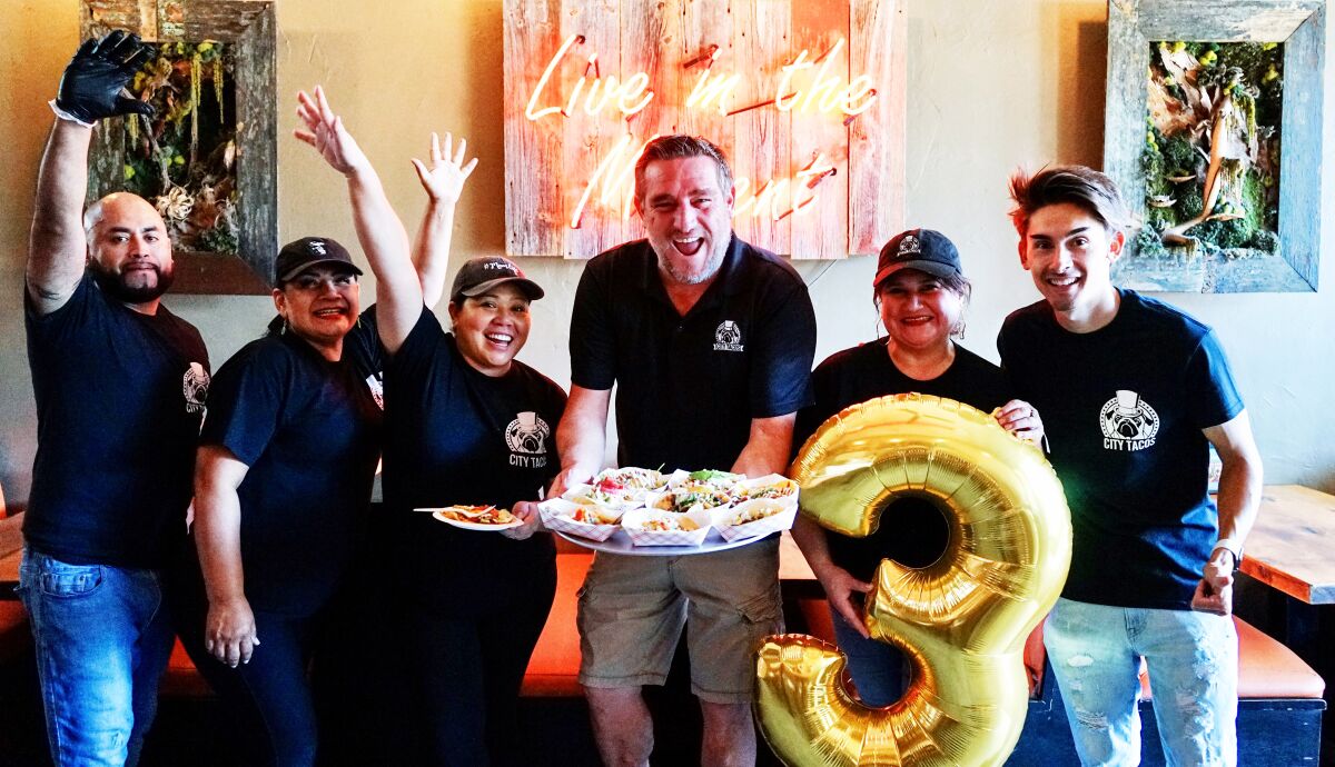City Tacos founder Gerald Torres, holding a tray of tacos, with employees in September 2023.